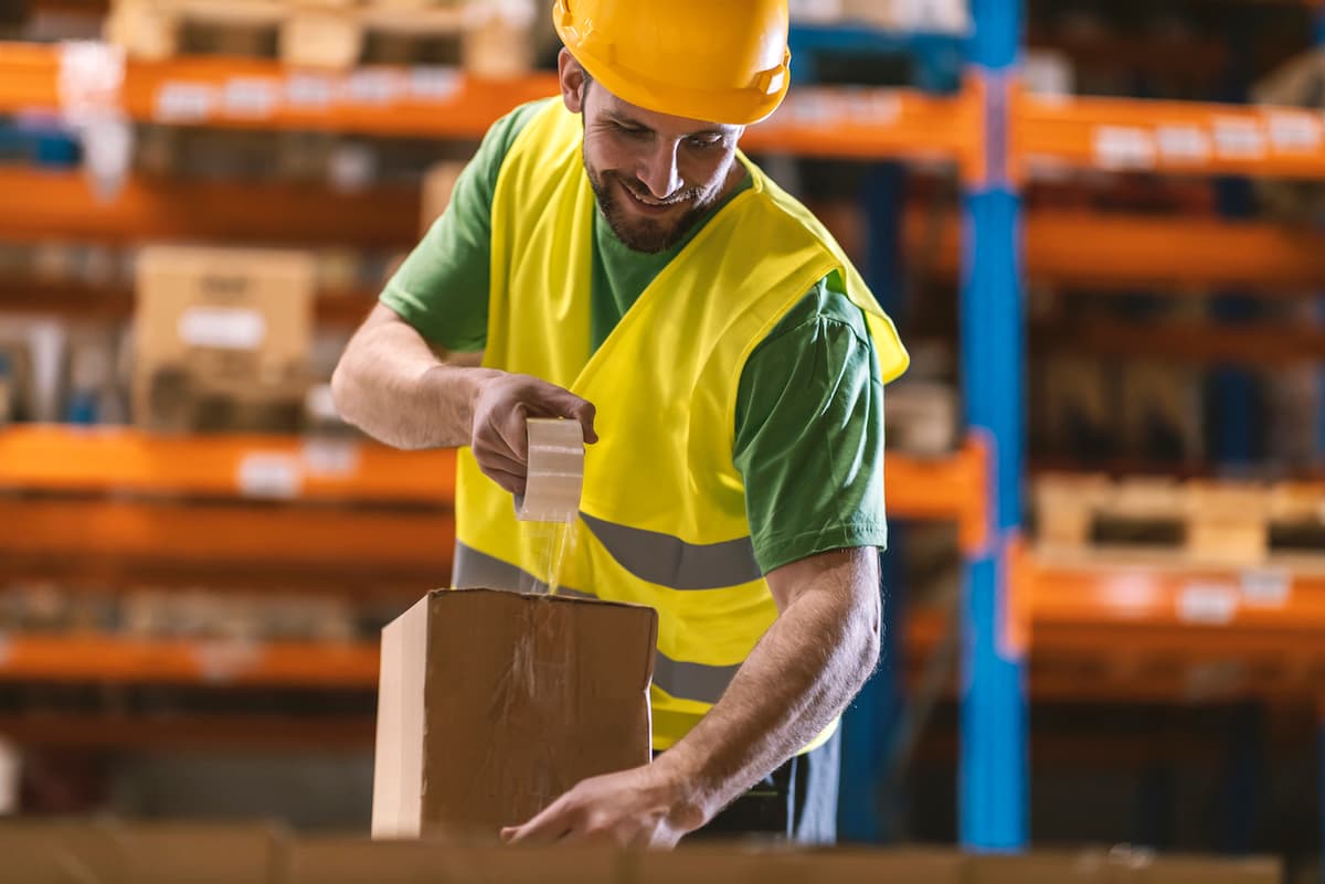 hombre en almacen empleando cintas acrilicas